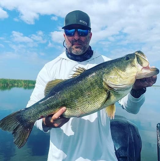 An angler on the water holding up a large bass