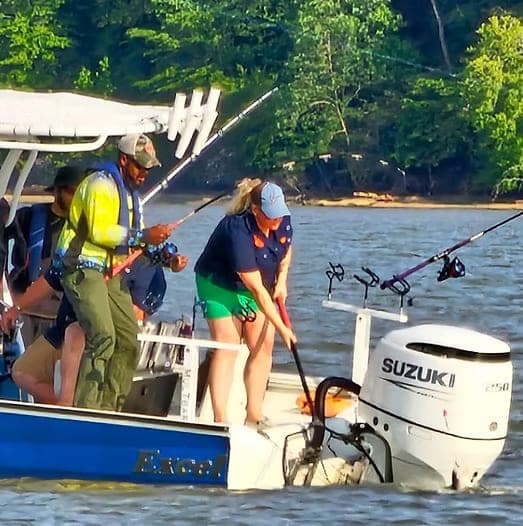 Participants fishing from the stern of a boat on the river