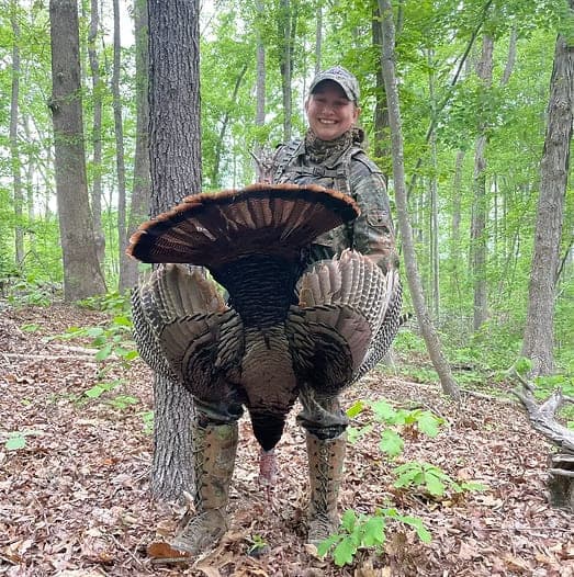 A hunter in the spring woods displaying a turkey fan