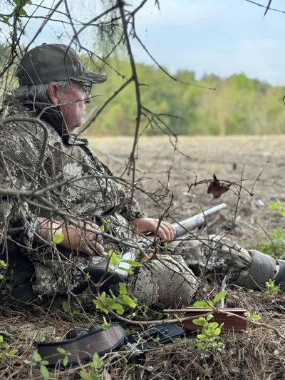 An older hunter waits in a brush blind during turkey season.