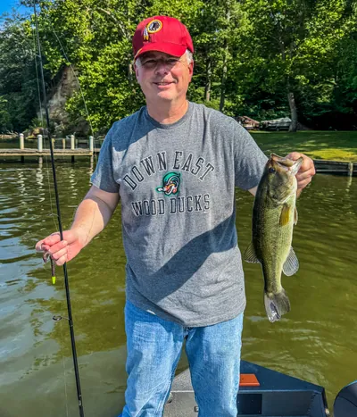 An angler holds up a bass by the docks.