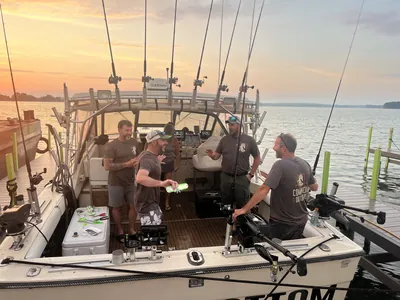 Participants in Comanche Outdoors shirts talk on a charter boat at dawn.