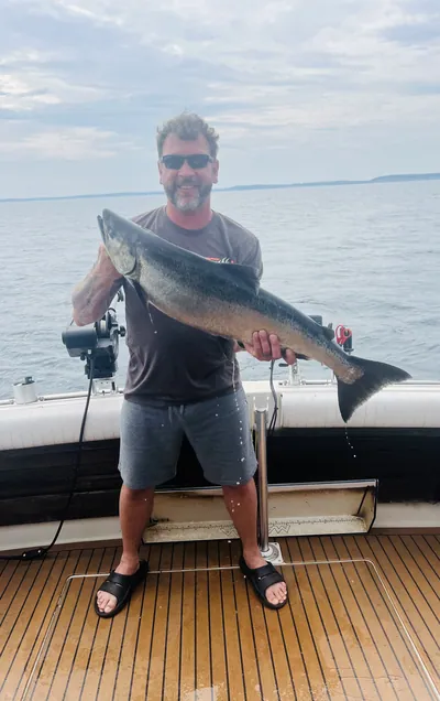 An angler holds a king salmon on a boat deck.