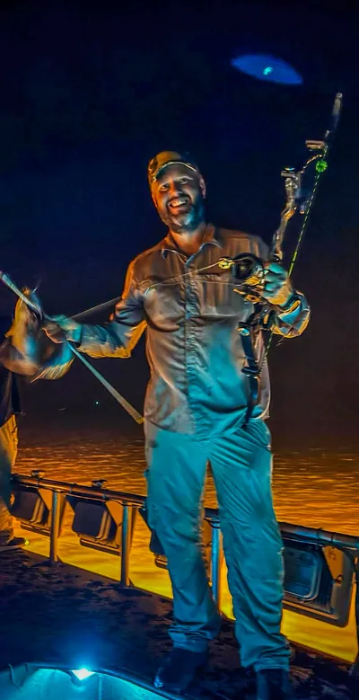 A bowfisher laughs on a boat.