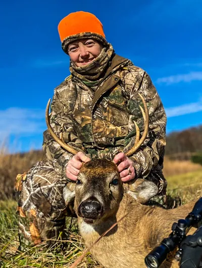 A smiling hunter poses with her buck.