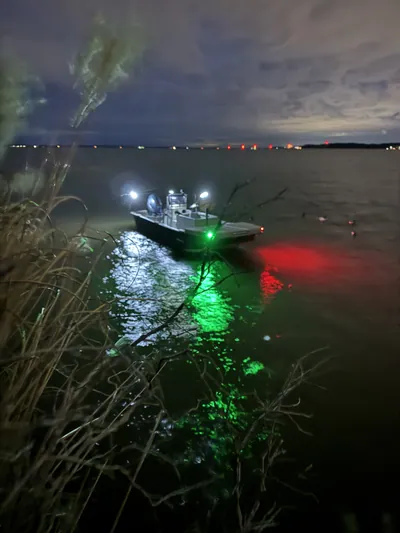 A boat's red and green lights glow on dark water before dawn.