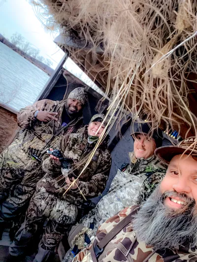 Four smiling hunters take a selfie in a duck blind.