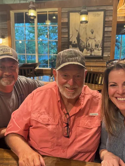 Three friends sit at a restaurant table.