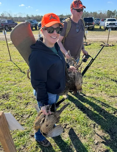 A smiling hunter carries her pheasants.