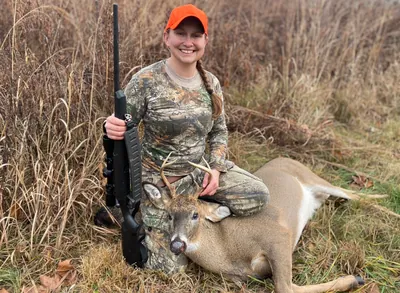 A smiling young hunter poses with her buck.