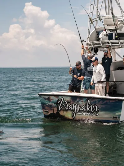 An angler fights a fish with a bent rod on a charter boat.